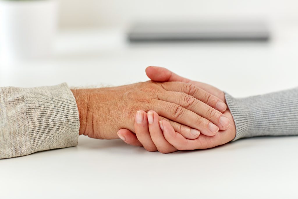 close up of old man and young woman holding hands