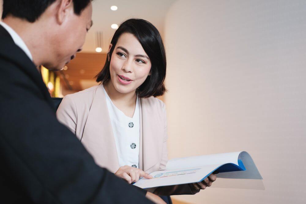 investment plan agent showing documents to asian customer in bank